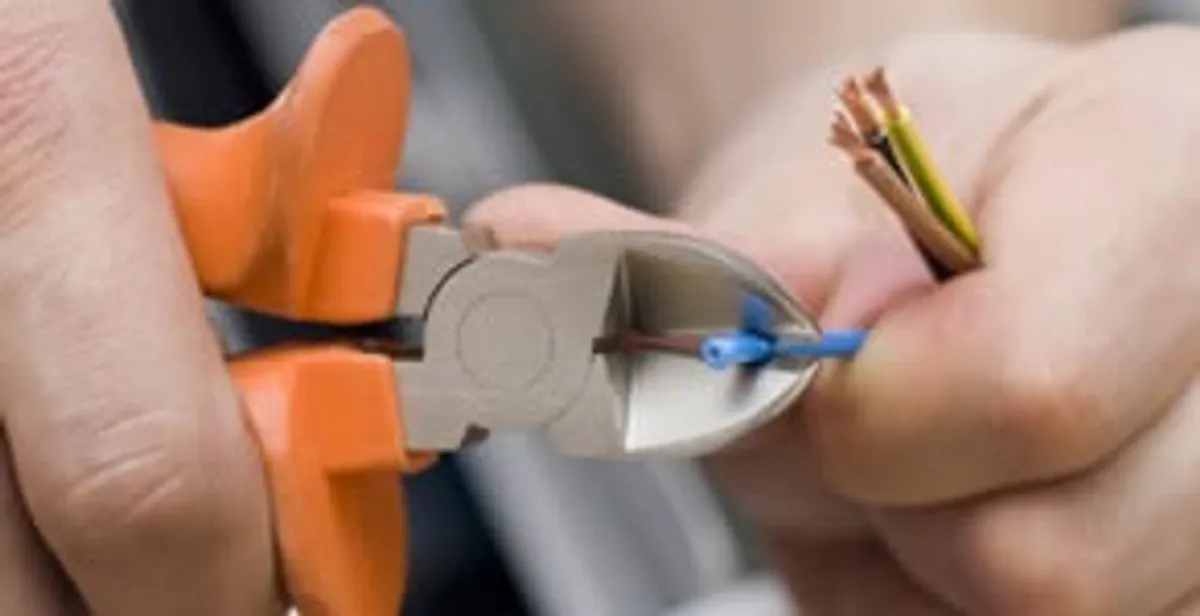 licensed electrician performing precise wire cutting and preparation during electrical service in Olathe, KS