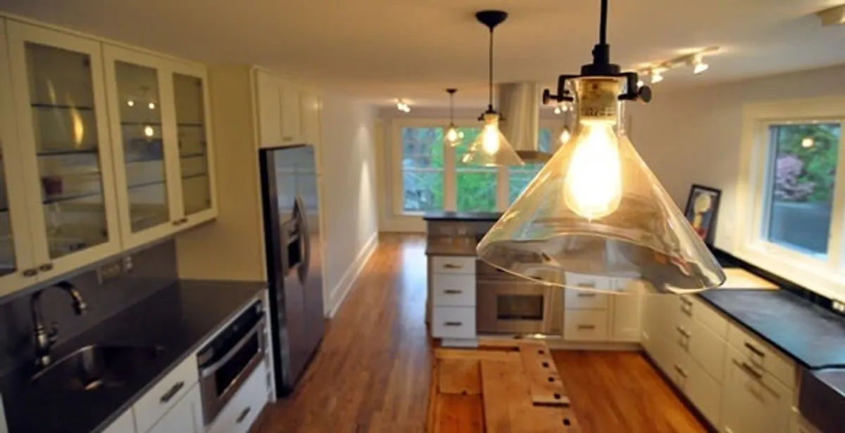 Residential electrician installing modern indoor light fixture in a home in Olathe, KS